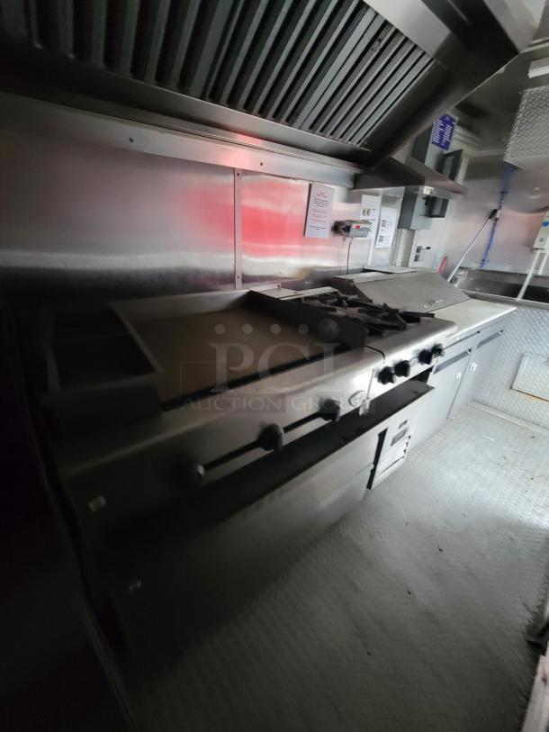 2019 Rock Solid 24' food trailer interior, featuring a commercial gas range and fryer under an exhaust hood.