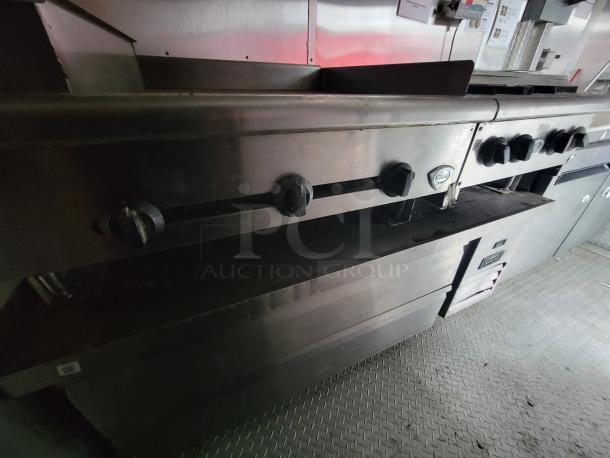 2019 Rock Solid Cargo food trailer interior showing commercial gas range and griddle under exhaust hood, in clean condition.