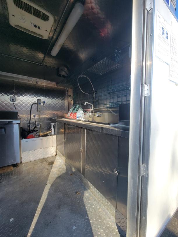 24' Quality Food Trailer interior, equipped kitchen with stainless steel sink, cabinets, and shelving, ready for use.
