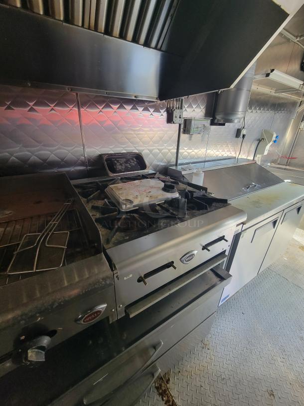 Professional-grade 24' food trailer interior, featuring a Wells stove, stainless steel surfaces, and diamond plate flooring.