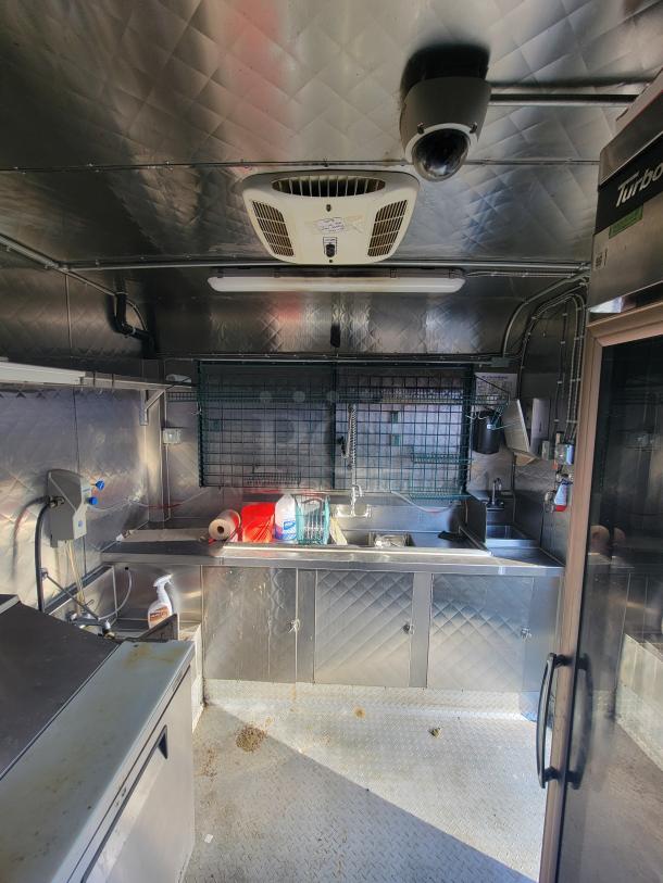 24' Quality food trailer kitchen interior, featuring commercial-grade stainless steel fixtures, sink, and storage. Fully equipped.