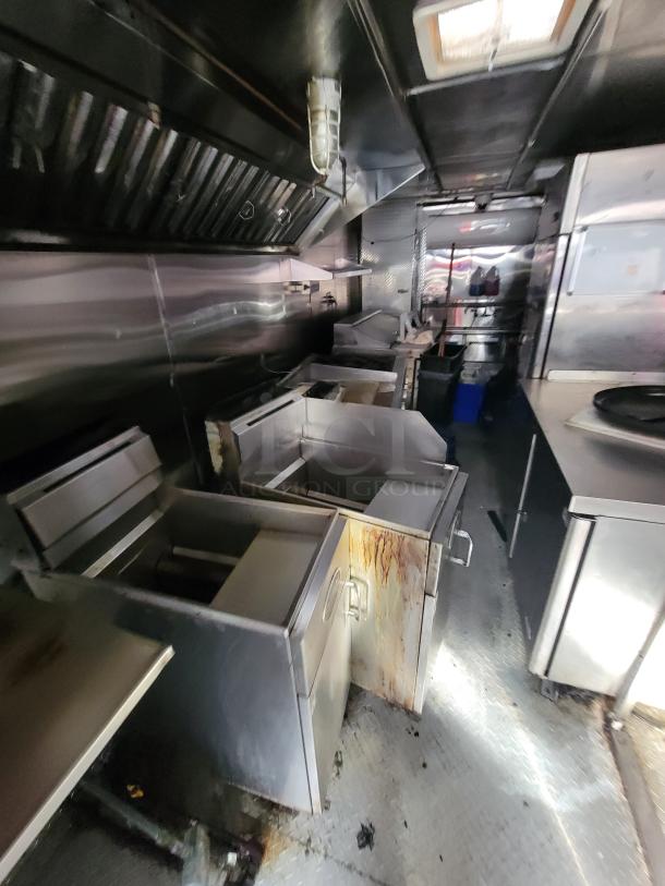 2019 Quality 24' food concession trailer interior with Royal gas range, stainless steel refrigerators, and prep tables.