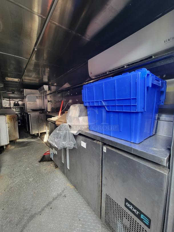 Interior of a 2019 Quality 24' food concession trailer, showing stainless steel prep tables and an Asber fridge.