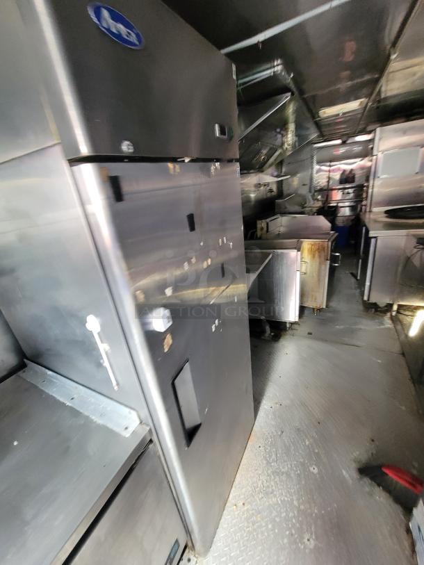 2019 Quality 24' food concession trailer interior, featuring stainless steel refrigerator, gas range, and prep tables.