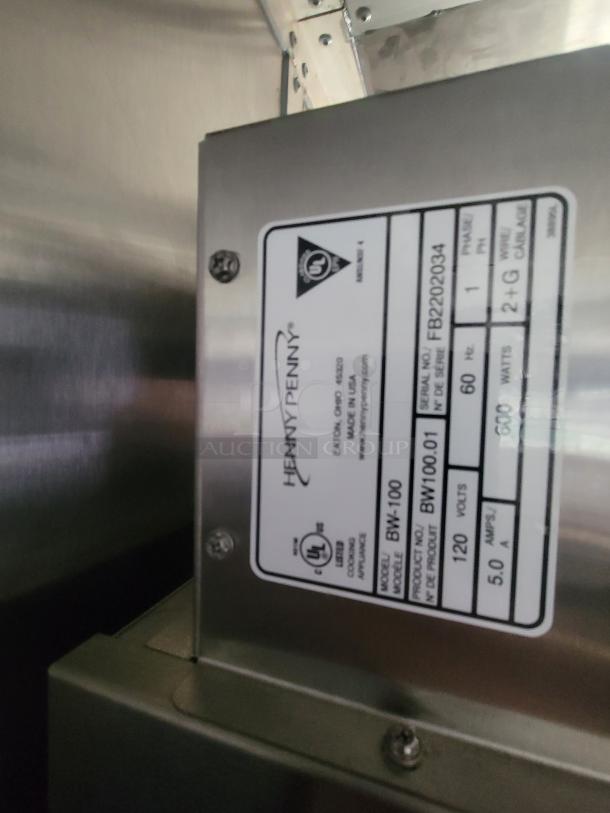 Label on a stainless steel appliance showing UL certification, Henny Penny branding, model BW-100, serial FB2202034.