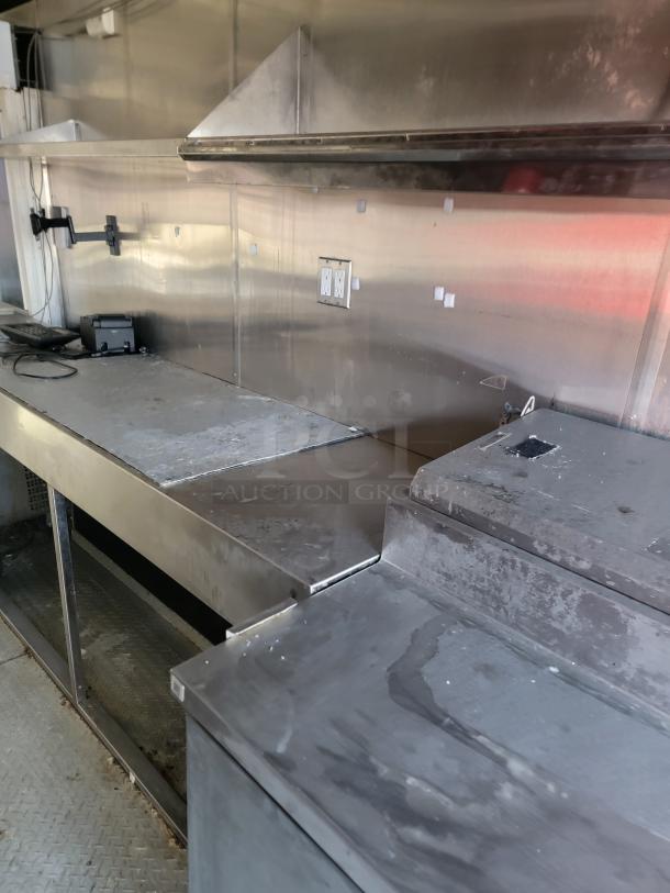 Interior view of a 2019 24' Quality food concession trailer with stainless steel surfaces, commercial prep tables, and outlets.