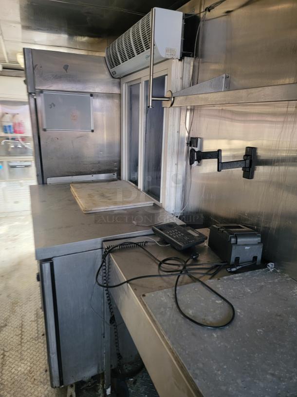 Interior of a 2019 Quality 24' Food Concession Trailer. Features commercial-grade stainless steel surfaces, phone, and equipment.