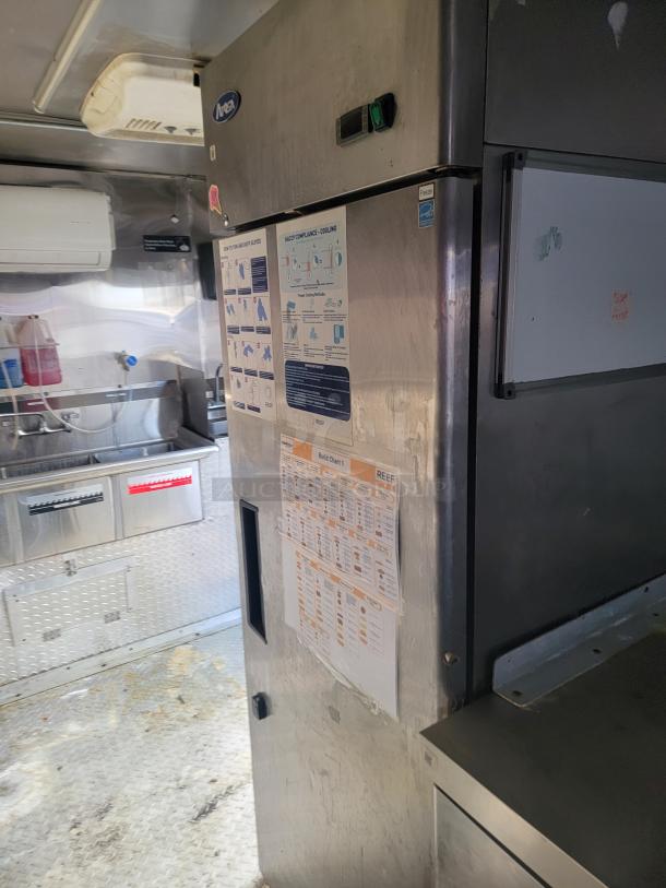 2019 Quality 24' food concession trailer interior. Features stainless steel fridge, prep area, and visible safety instructions.