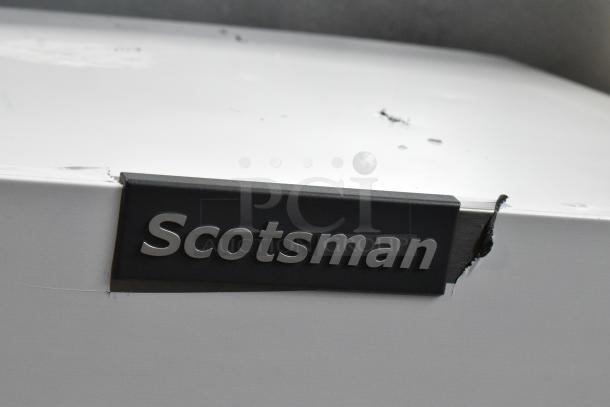 Scotsman MC0330MA-1A ice machine label, showing brand logo. Scratch visible on white surface near label.