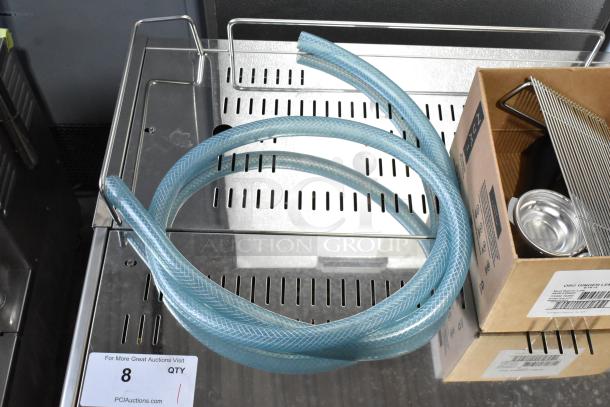 Stainless steel Estella ECEM2 espresso machine with 3 portafilters, steam wands, and blue hosing. New scratch and dent condition.