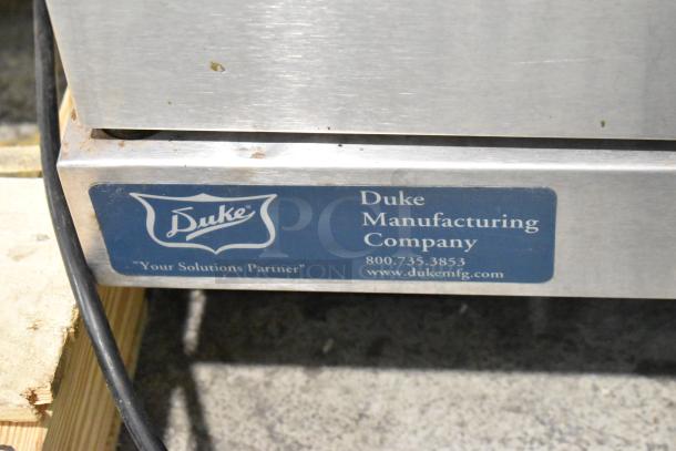 Duke 613-G2V stainless steel convection oven with solid door, metal racks, and thermostatic controls. Duke label visible.