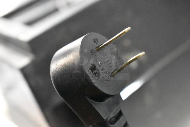 Close-up of a standard electrical plug end, likely associated with the Delfield cooler, showing surface wear.