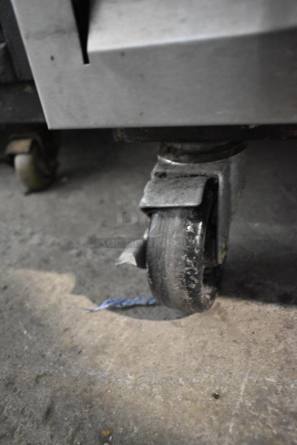 Beverage Air commercial cooler caster, showing wear. Stainless steel construction, on wheels for mobility. 115V, 1 phase.