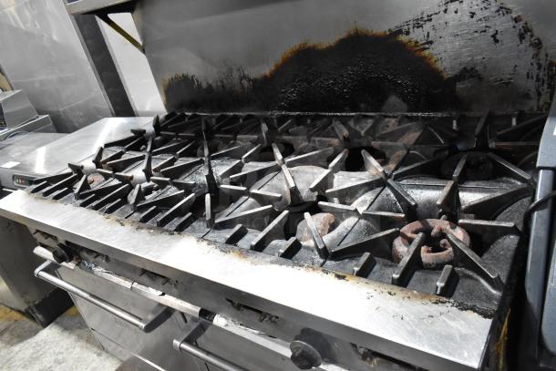 Garland SunFire stainless steel commercial gas range with 10 burners, 2 ovens, over shelf, backsplash, on commercial casters.