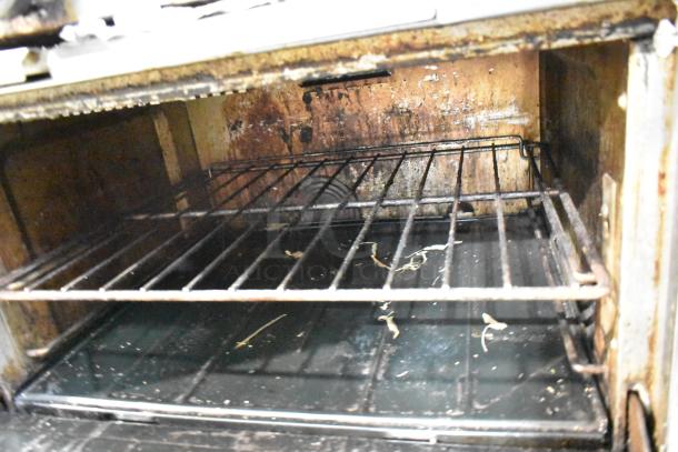 Garland SunFire commercial gas range oven interior, showing used condition with visible grime and residue on racks and walls.