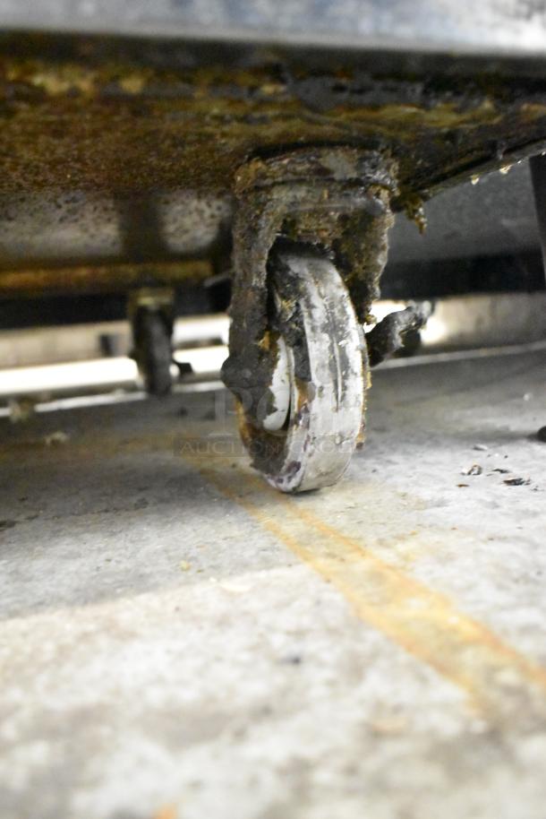 Close-up of a rusty, worn caster on a Garland SunFire commercial range.