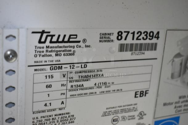 Label on the 2016 True GDM-12-LD cooler showing model, 115V, 1 phase, refrigerant R134A, cabinet serial number 8712394.
