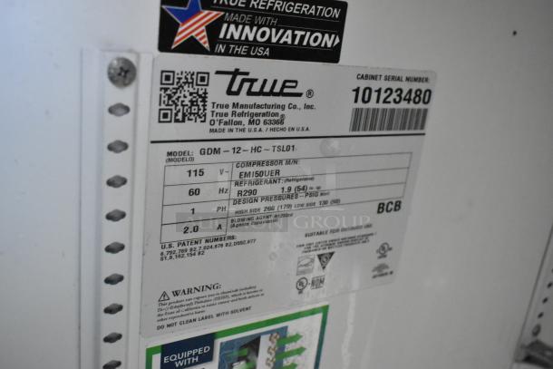Label on True GDM-12-HC cooler showing model, voltage (115V), refrigerant details, and manufacturing info.