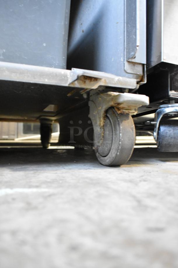 JBT 2ND-GEN-MFJ-HE citrus juicer on commercial casters; visible wear on wheels, sturdy stainless steel build.