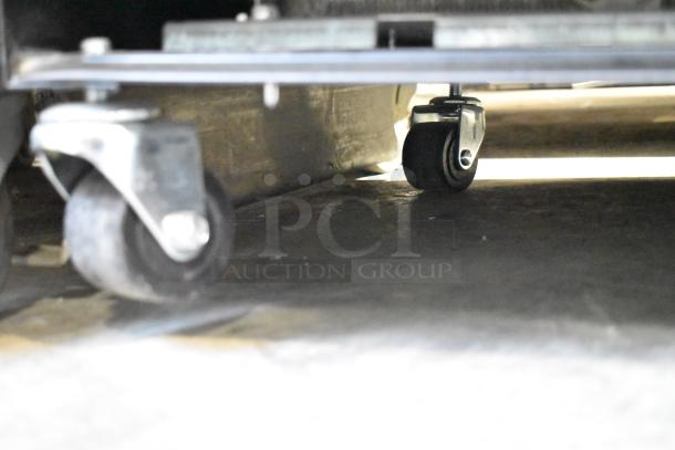 Underneath view of True T-19F-HC commercial freezer showing steel casters and part of the base.
