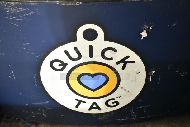 Metal commercial floor-style animal tag engraving machine featuring a "Quick Tag" label. Surface shows wear and scratches.