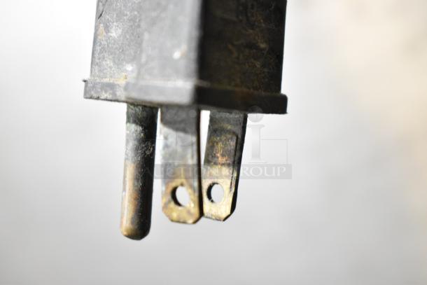 A close-up of an electric plug prong shows signs of wear and corrosion, indicating potential need for replacement or repair.