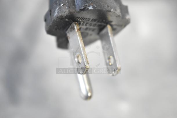 Close-up of a standard two-prong electrical plug with visible wear on metal prongs.