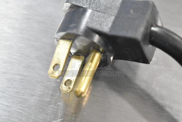 Close-up of a power cord plug for Beverage Air UCR48A cooler, showing prongs and black casing on a stainless steel surface.