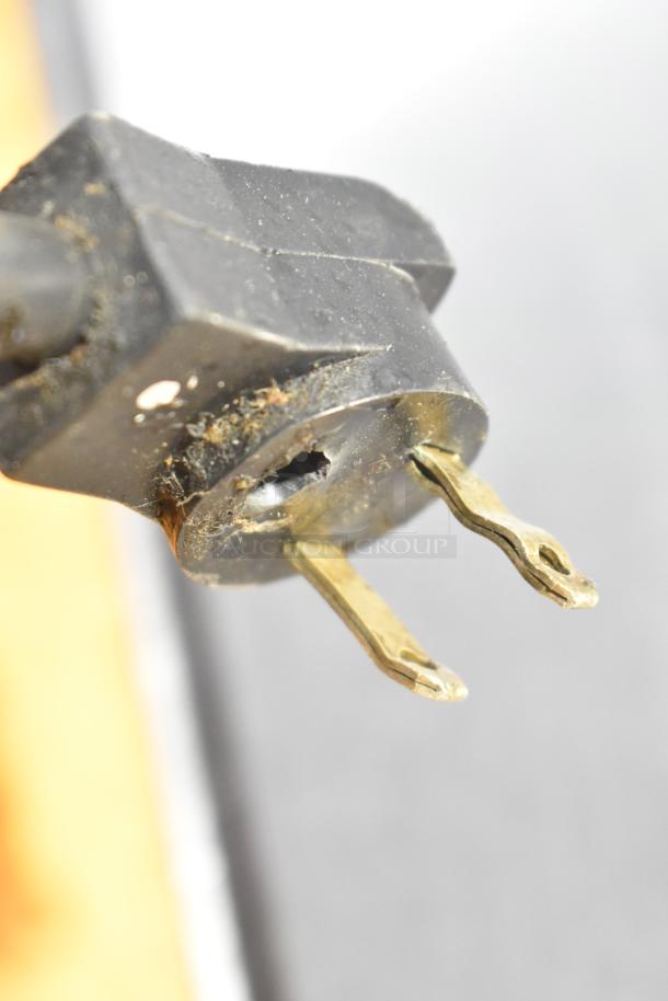 Close-up image of a power plug with two prongs, showing wear and dust accumulation.