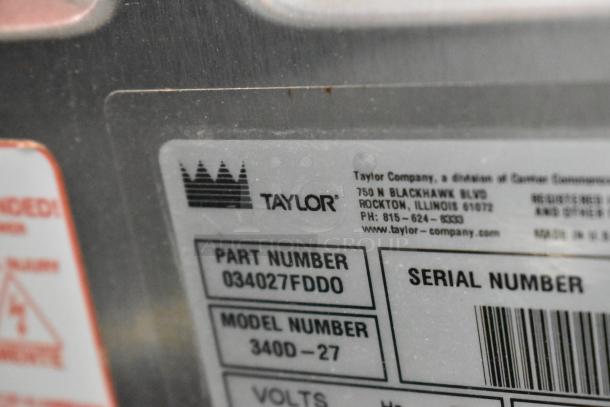 Label on Taylor 340D-27 stainless steel frozen beverage machine; shows part and model numbers, contact info, and voltage details.