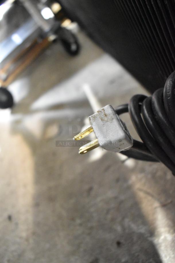 Close-up of power plug for True GDM-41SL-60-HC-LD cooler, 115 volts, showing metallic prongs and black cord.