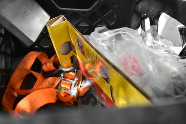 Assorted items in a crate including orange straps, a pelican headpiece, and a yellow boxed item. Mixed condition.