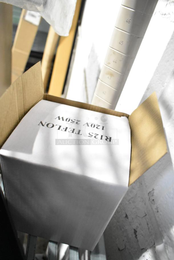 Box labeled "RIS Teflon 120V 250W" open in storage area, part of auction lot including pelican headpiece and rack.