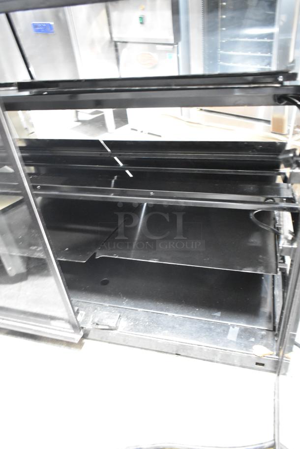 Metal countertop dry merchandiser display case, 115 volts, 1 phase, with glass doors and shelves, excellent condition.