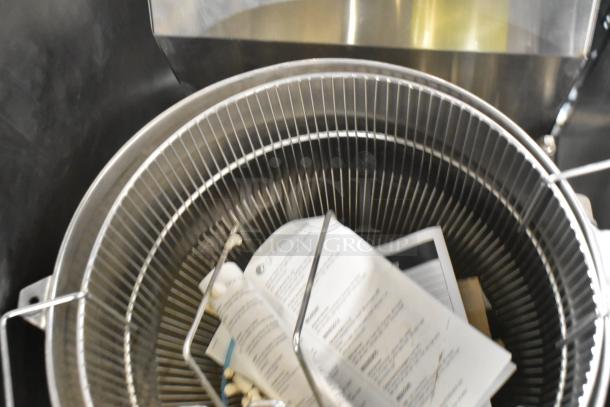 Groen stainless steel commercial steam kettle, floor style, featuring wire cage insert and visible documents inside.