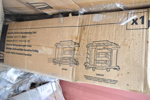 Cardboard box containing a Rubbermaid® 2202527 Full Size Housekeeping Cart with Accessory Bundle, featuring model illustrations.