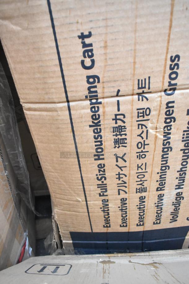 Cardboard box labeled "Executive Full-Size Housekeeping Cart," indicating a Rubbermaid 2202527 item inside.