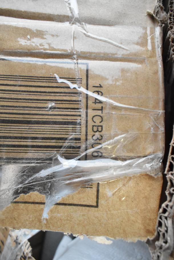 Cardboard box corner with barcode and code "164TCB306" visible, wrapped in clear tape, displaying signs of wear.