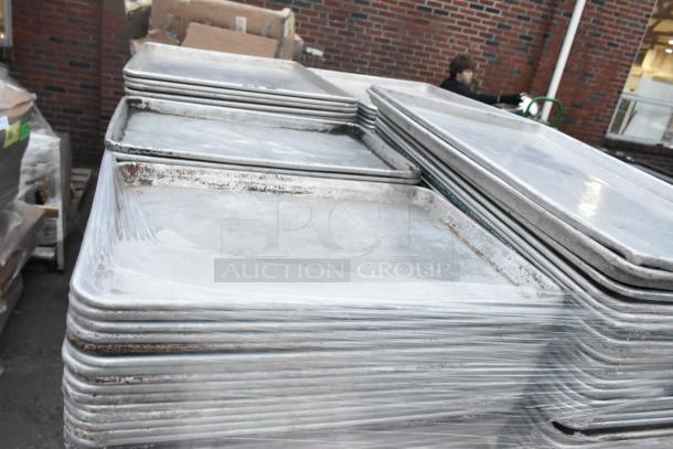 Stack of 600 metal full-size baking pans, showing wear, bundled on a pallet. Bidding multiplies by 600.