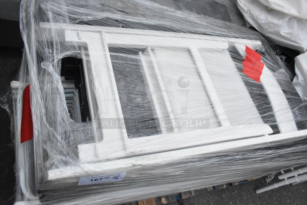 48 white and black folding chairs, shrink-wrapped on a pallet. New condition. Auction tag labeled "167."