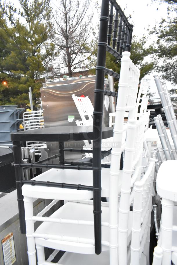 62 Chiavari stackable banquet chairs in black and white, shown stacked outdoors. Ideal for events, minor wear visible.