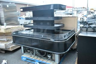 Black metal island-style Grab N Go merchandiser, multi-tiered design, freestanding, used condition, visible wiring underneath.