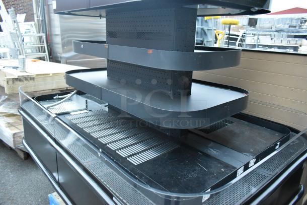 Black metal island-style Grab N Go merchandiser with multiple shelves. Features perforated back panels; good condition.