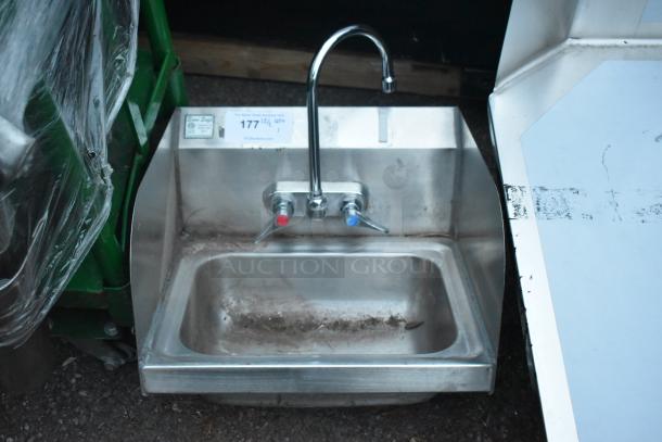 Stainless steel single bay sink with faucet, dual handles, and side splash guards. Visible signs of dirt and wear.
