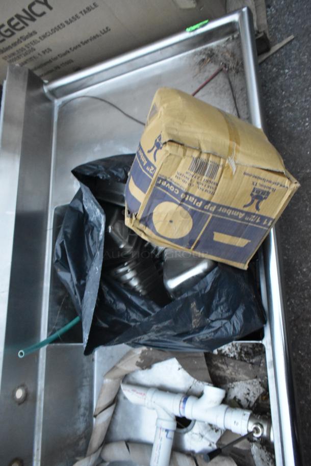 Stainless steel 3 bay sink with dual drain boards, no legs, shown with assorted items.