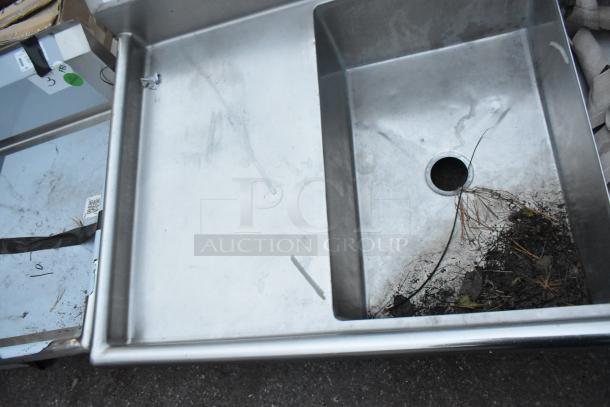 Stainless steel 3 bay sink with dual drain boards, no legs. Slightly worn condition, visible dirt in basin.