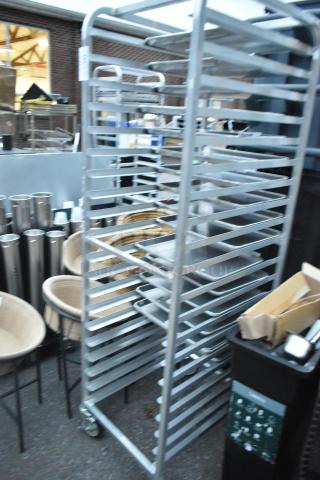 Metal portable pan rack with multiple shelves on commercial casters, used condition. Ideal for bakery or kitchen use.