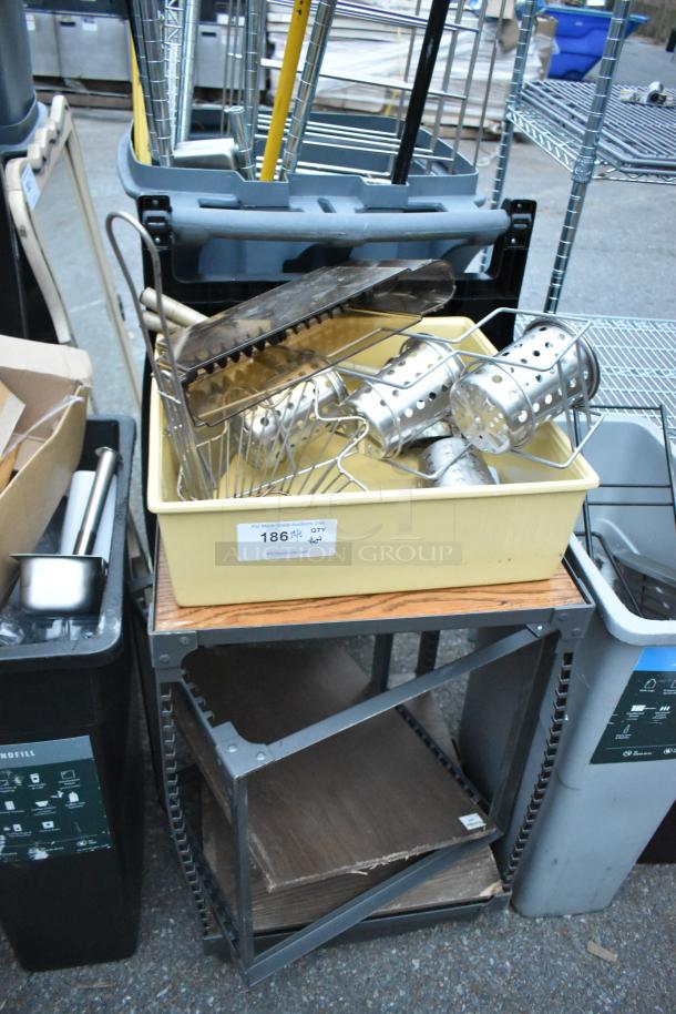 Assorted items including trash cans, a bin, metal racks, and a table with contents. Some wear visible. Label reads "186, QTY 6".