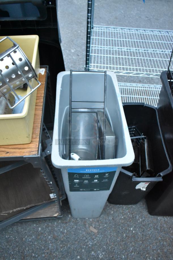 Assorted items including trash cans, a bin, a table, and various contents. Items show visible wear, black and grey colors.
