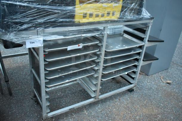 Metal commercial double pan transport rack with commercial casters, containing multiple trays, wrapped in plastic.